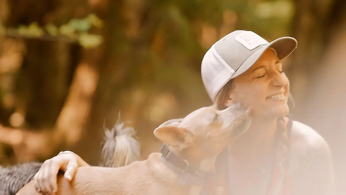 Alexx laughing as one of her dogs reaches up to her face