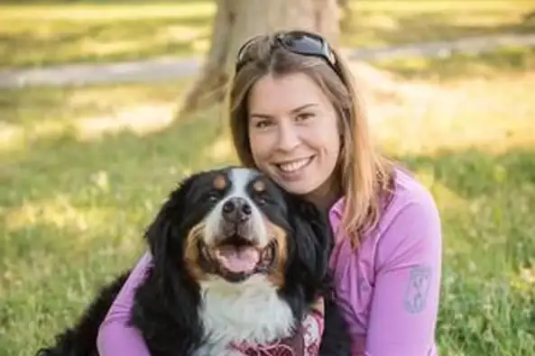 Jessye smiling cheek to cheek with her Bernese mountain dog
