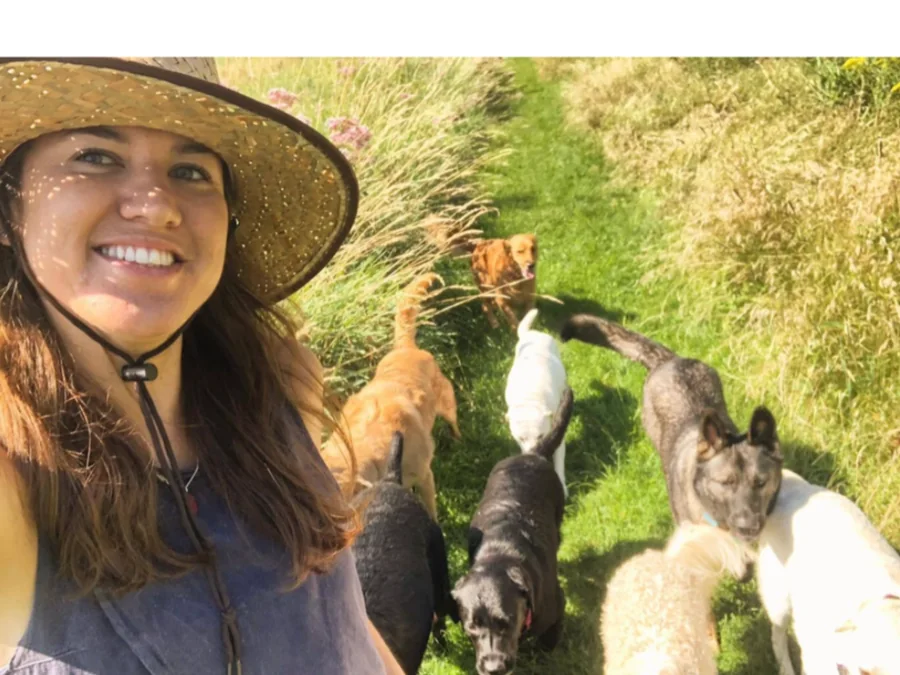 Rhonda Bilodeau smiling in her sun hat with her dog camp pack on a summer trail